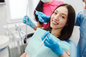 Smiling patient in dental chair receiving care from dentist and dental assistant, showcasing a supportive environment for overcoming dental anxiety.
