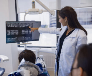 Dentist showing dental X-rays on a screen to a patient, emphasizing tooth health and sensitivity management at Smiles of Chevy Chase.