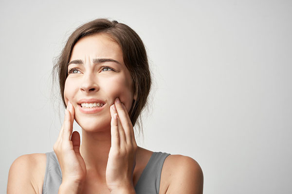 Woman experiencing jaw pain and discomfort, illustrating TMJ disorder symptoms.